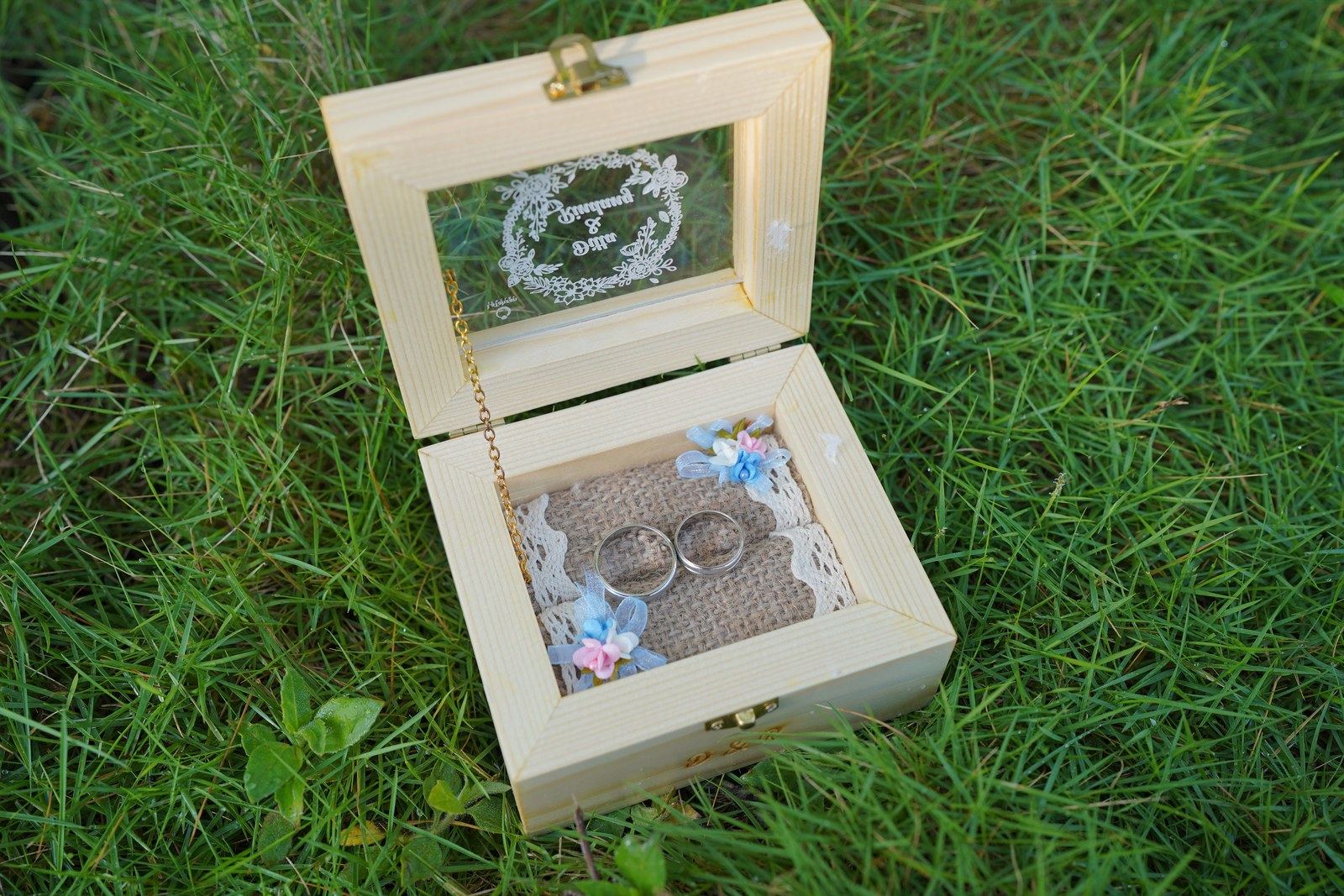 Wedding rings displayed in a personalized wooden ring box outdoors