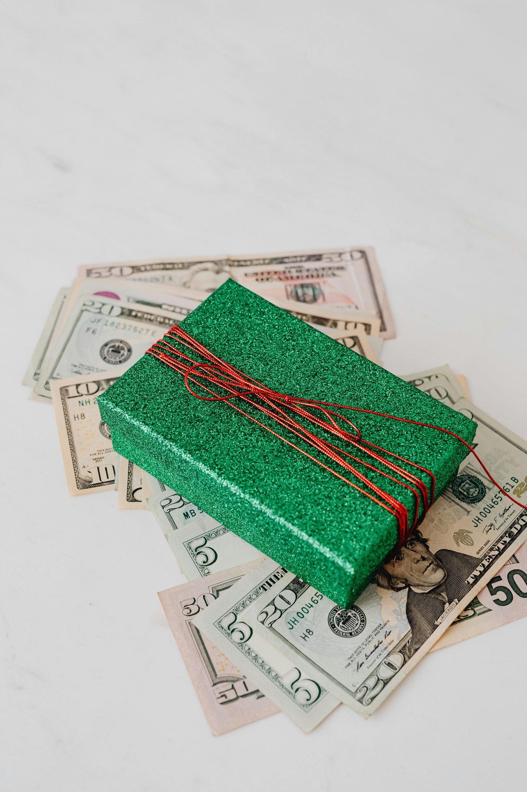 Green wrapped present placed on dollar bills.