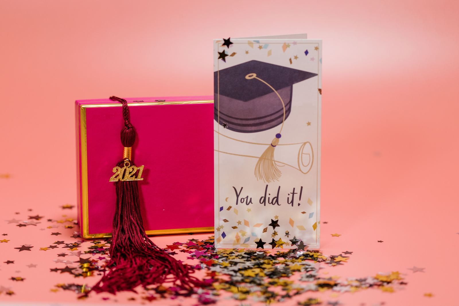 Carte de remise de diplôme, pompon et boîte cadeau lumineuse arrangés avec des confettis